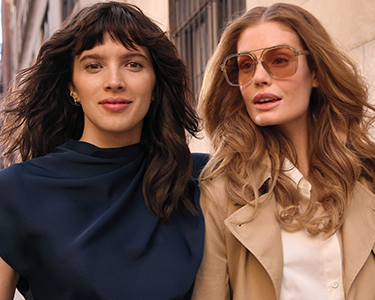 woman with brown hair and woman with red hair wearing sunglasses walking along the street in new york city