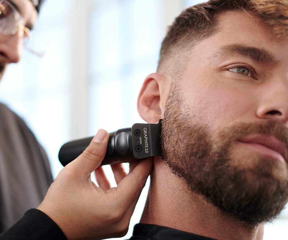 hombre con barba con cortadora de cabello en negro