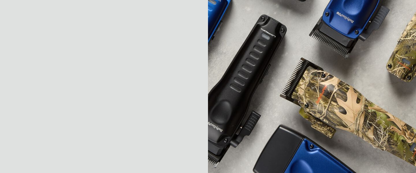 Professional barber clippers and trimmers in black, blue, and camouflage designs rested on a light concrete background.