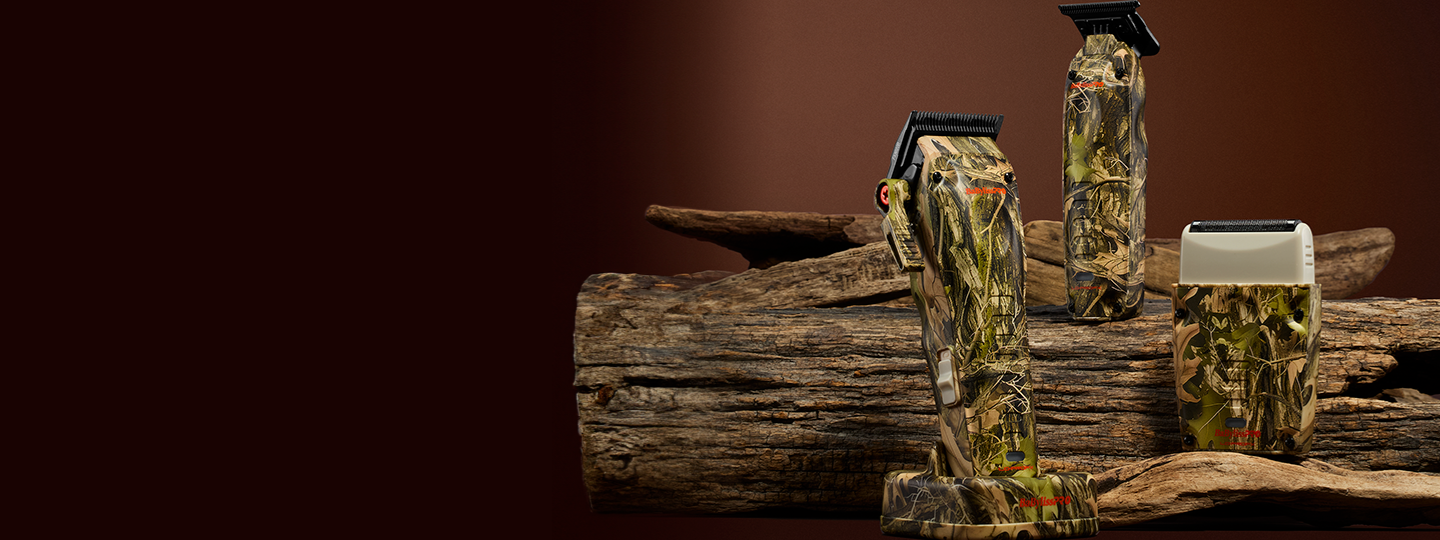 Tres herramientas de cuidado personal con estampado de camuflaje (una afeitadora, una cortadora de cabello y una recortadora) se exhiben sobre una superficie de madera rústica rodeada de hojas.