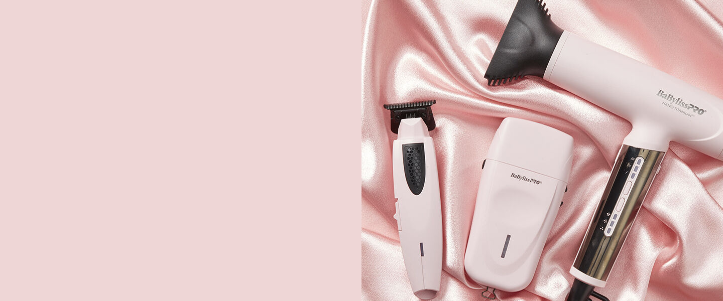 Afeitadora de hoja y recortadora color rosa y secador de cabello sobre un fondo rosa con aspecto sedoso