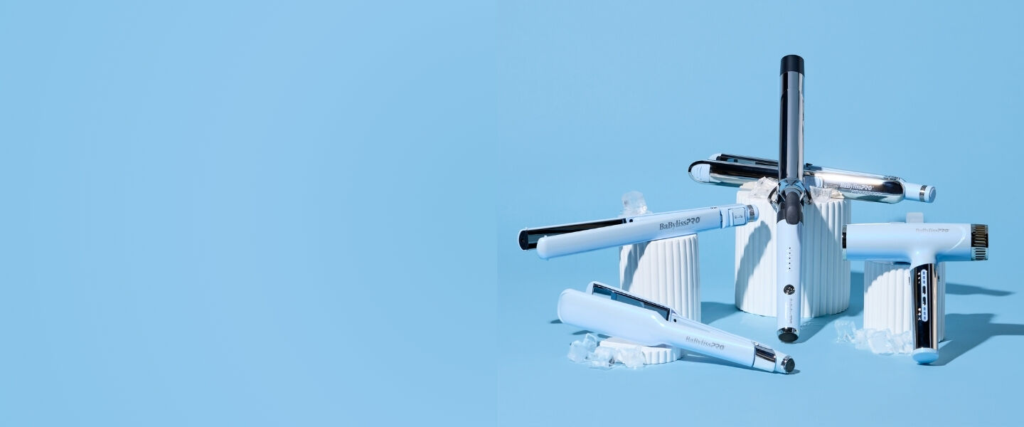 Light‑blue BaBylissPRO hairstyling tools&mdash;including a flat iron, curling wand, and two hair dryers&mdash;are arranged in a radial display on top of white textured pedestals, set against a solid light‑blue background with scattered ice cubes for a cool‑toned aesthetic