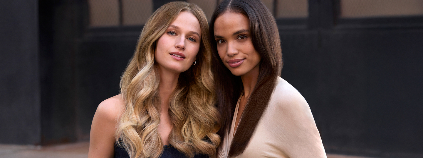 Two female models with long, smooth hair standing side by side.