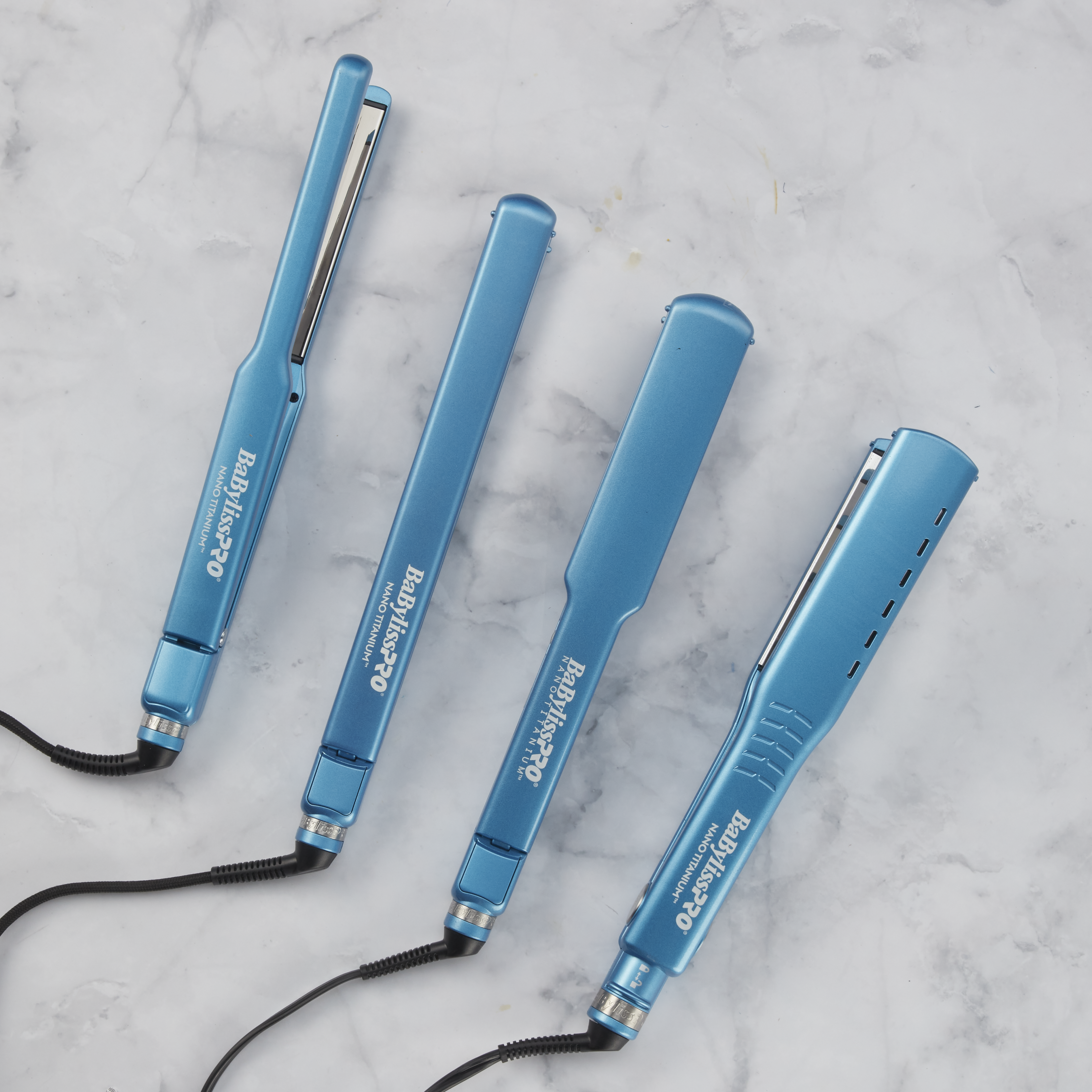 image features 4 babylisspro nano titanium flat irons in a blue colorway laying flat on a marble counter